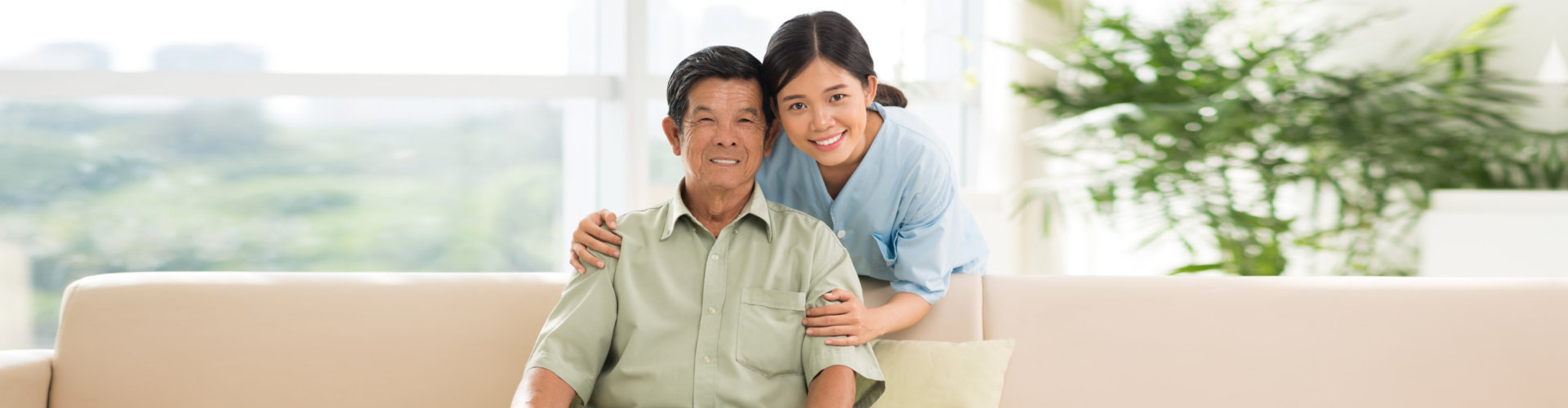 elder man sitting on the couch with caregiver behind him